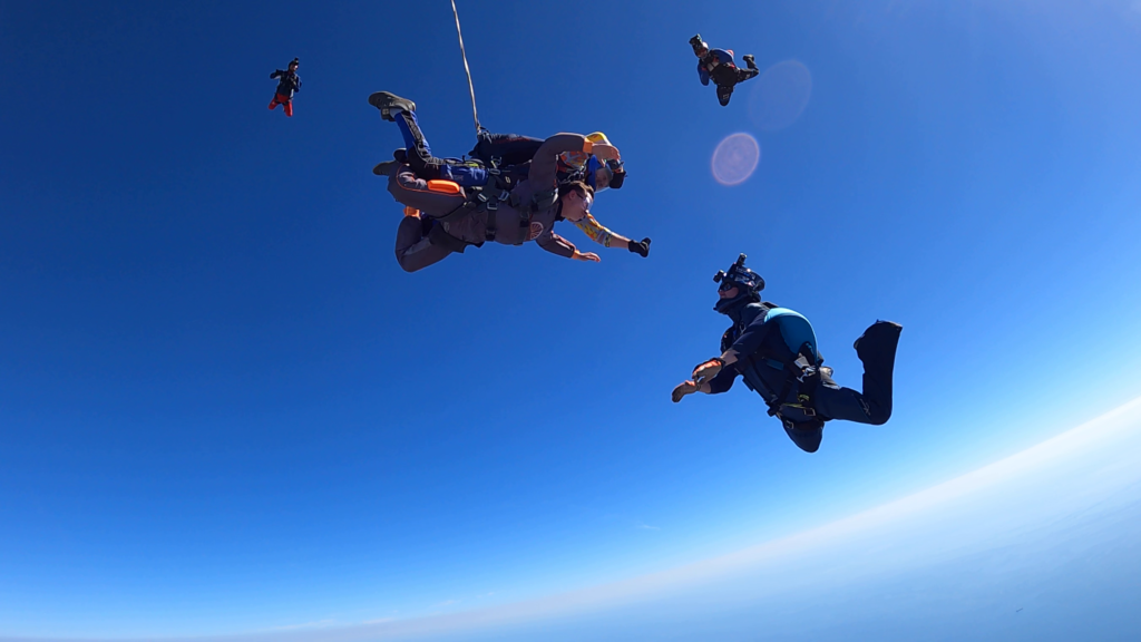 Tandem skydiving with camera person filming